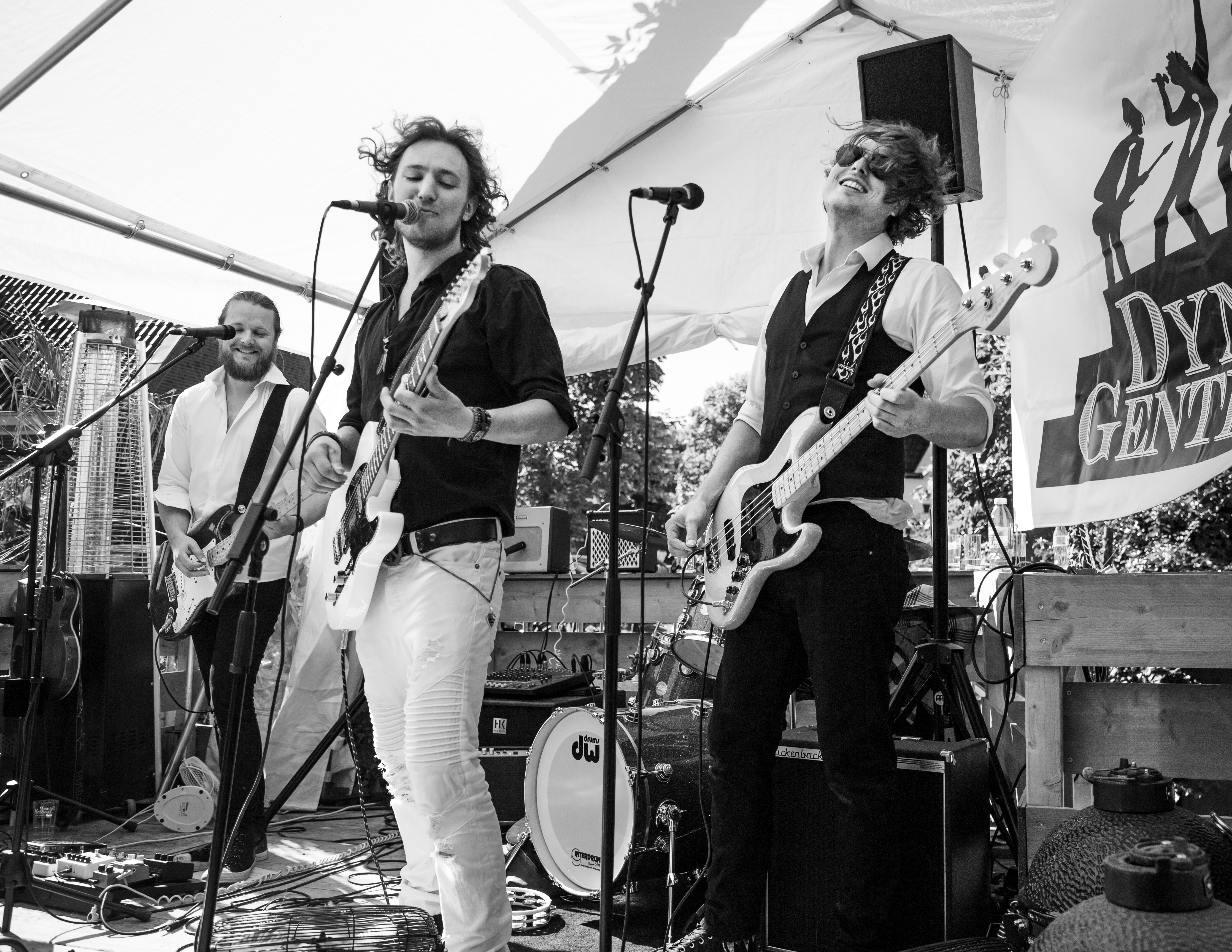 Dramatic wide shot of a rock band silhouette on stage with golden backlighting and atmospheric smoke
